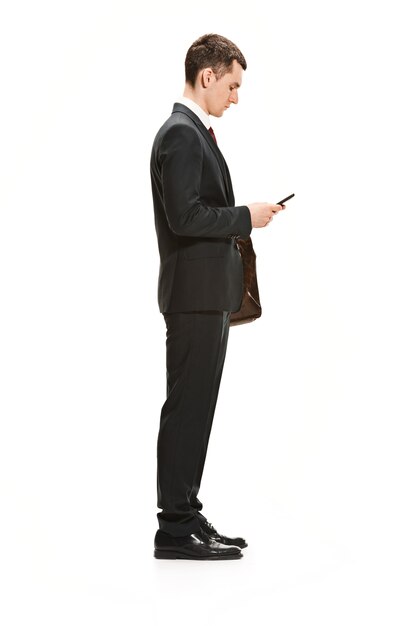 Homme d'affaires avec dossier bavardant sur le smartphone isolé sur mur blanc