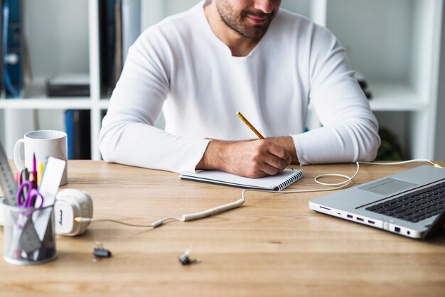 Homme d&#39;affaires, écrit sur le bloc-notes sur un bureau en bois