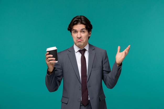 Homme d'affaires élégant mignon bel homme en costume de bureau gris et cravate en agitant les mains avec une tasse en papier