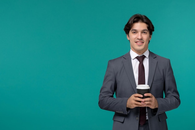 Homme d'affaires élégant mignon bel homme en costume de bureau gris et cravate tenant avec deux mains café