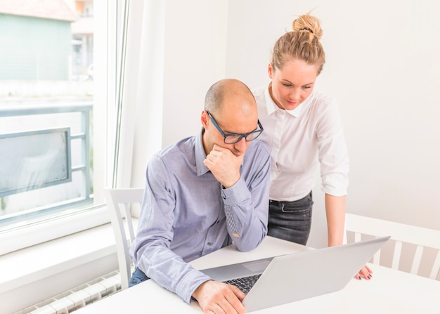 Photo gratuite homme d'affaires envisagé et femme d'affaires regardant un ordinateur portable