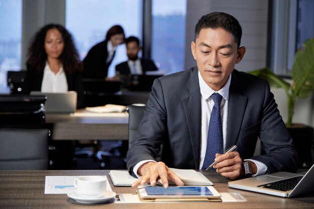 Homme d'affaires ethnique concentré à l'aide de tablette