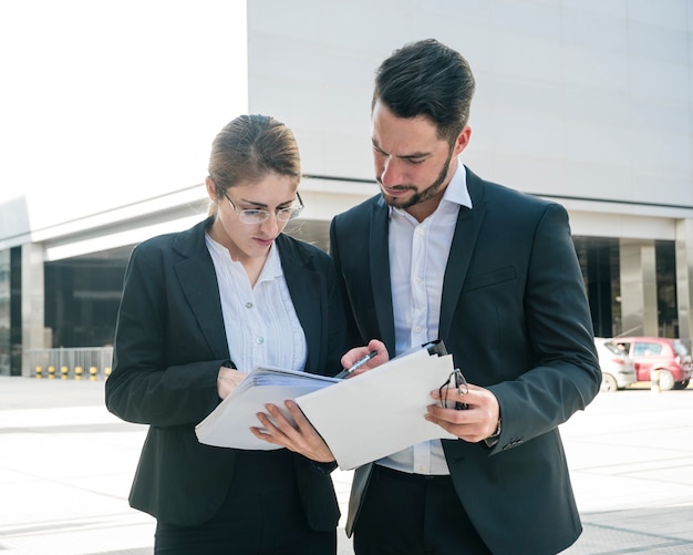 Homme d&#39;affaires et femme d&#39;affaires vérifiant les documents à l&#39;extérieur