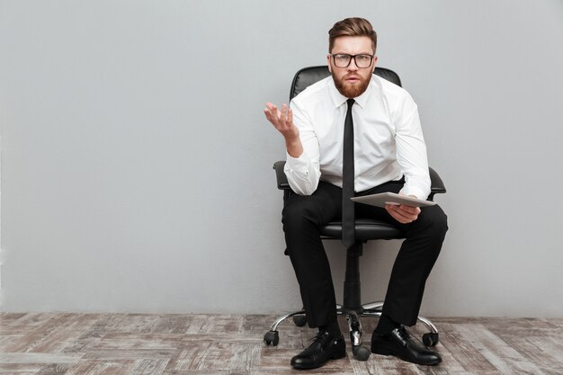 Homme d'affaires frustré mécontent à lunettes tenant la tablette pc