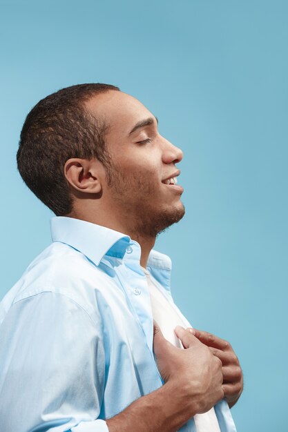 homme d'affaires heureux debout et souriant contre le bleu