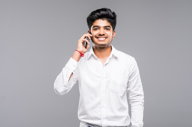 Homme d'affaires indien souriant appelant sur smartphone sur mur gris