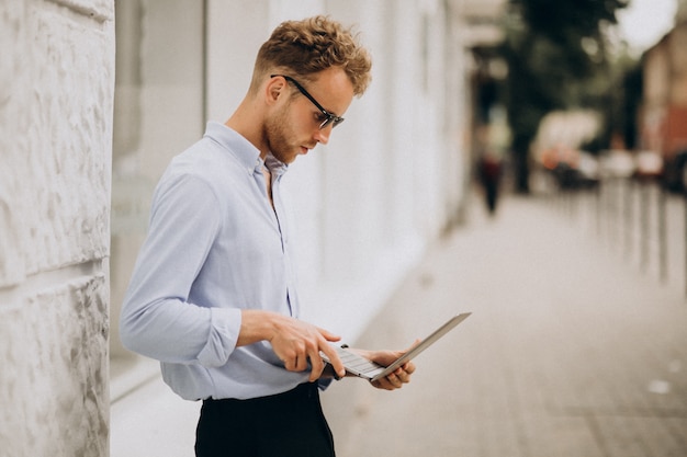 Homme d'affaires jeune avec ordinateur portable dans la ville