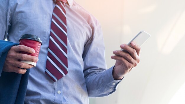 L&#39;homme d&#39;affaires jeune et prospère lit un message sur son smartphone.