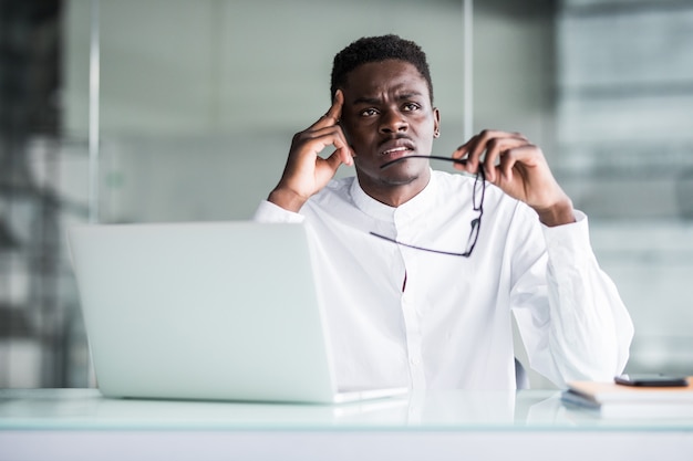 Homme d'affaires jeune sur son lieu de travail ressentir des maux de tête toucher la tête avec les mains. Travail de stress