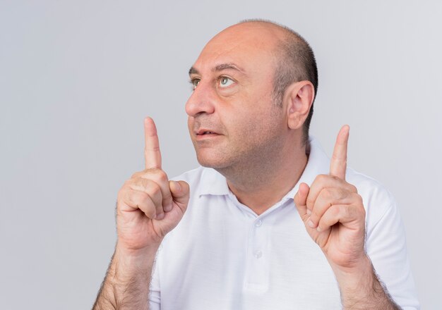 Homme d'affaires mature occasionnel impressionné regardant le côté et pointant vers le haut isolé sur fond blanc