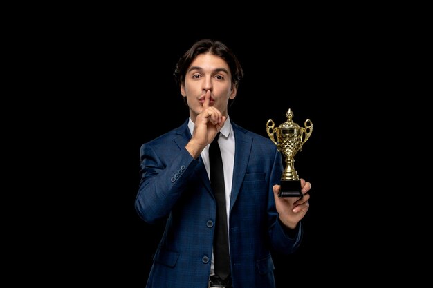 Homme d'affaires mignon mec brune en costume bleu foncé avec la cravate montrant le signe du silence