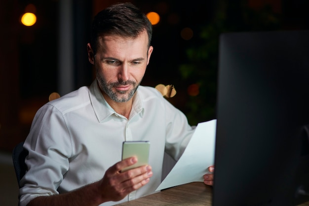 Homme d'affaires mûr utilisant le téléphone portable la nuit