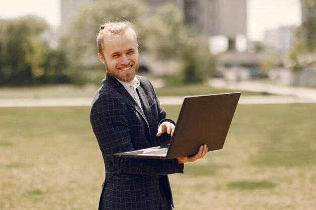 Homme d'affaires avec ordinateur portable dans une ville d'été