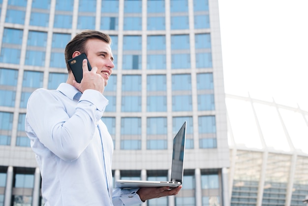 Homme d'affaires, parler au téléphone tout en tenant un ordinateur portable