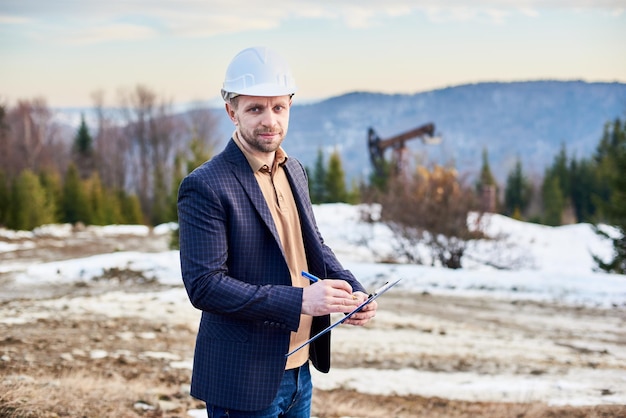 Photo gratuite homme d'affaires pétrolier tenant presse-papiers et stylo