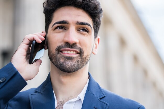 Homme d'affaires professionnel parlant au téléphone tout en marchant à l'extérieur dans la rue.