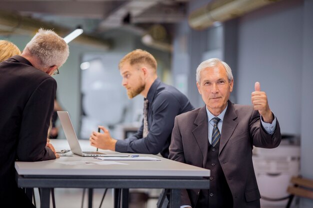 Homme affaires, projection, pouce haut, signe, séance, devant, son, équipe, discuter, bureau