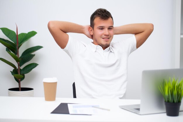 Un homme d'affaires prospère en chemise blanche travaille au bureau de l'entreprise sur un ordinateur portable.