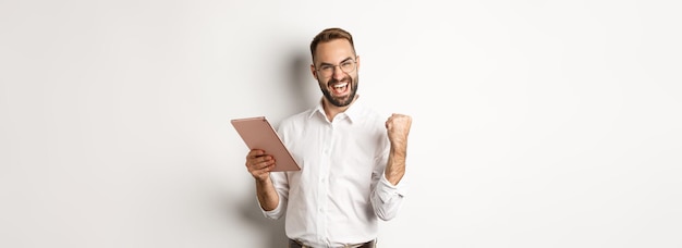 Homme d'affaires prospère se réjouissant de gagner la lecture en ligne sur tablette numérique et de faire la pompe à poing tr