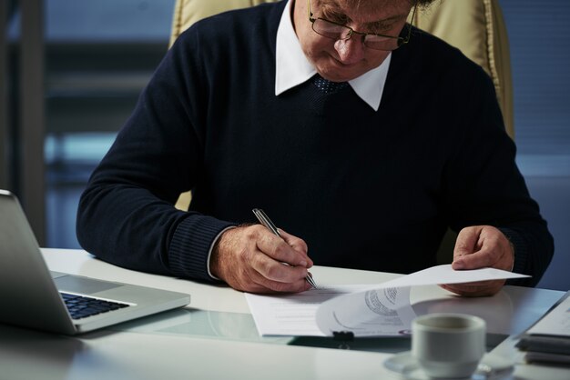 Homme d'affaires recadré examinant des documents pour la vente d'entreprise