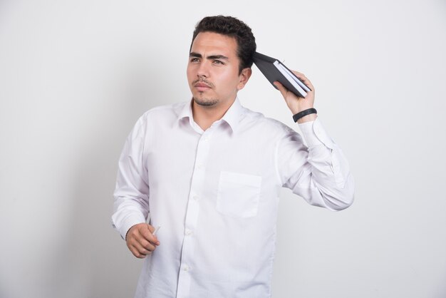 Homme d'affaires réfléchi avec ordinateur portable debout sur fond blanc.