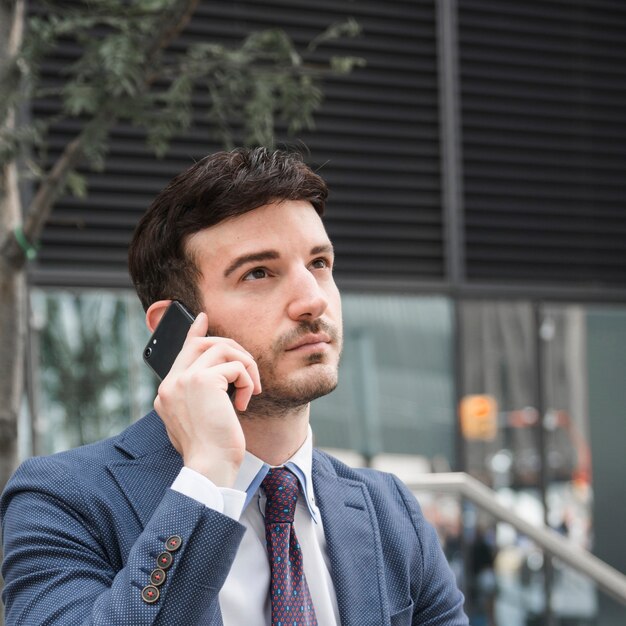 Homme d&#39;affaires réfléchi parlant sur smartphone