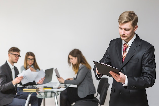 Homme d&#39;affaires en regardant le document sur le presse-papiers au lieu de travail