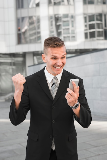 Homme d&#39;affaires en regardant smartphone avec expression joyeuse