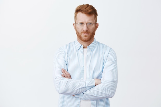 Homme d'affaires riche et sérieux en chemise et lunettes, fronçant les sourcils à la recherche stricte avec une expression calme et déterminée, croisant les mains sur la poitrine, écoutant attentivement pendant l'affaire