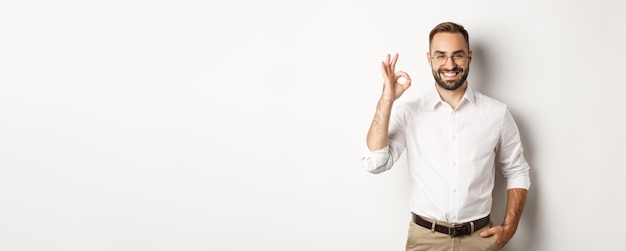 Photo gratuite un homme d'affaires satisfait souriant et montrant un signe ok approuve et aime quelque chose de bien debout au-dessus de la pentecôte