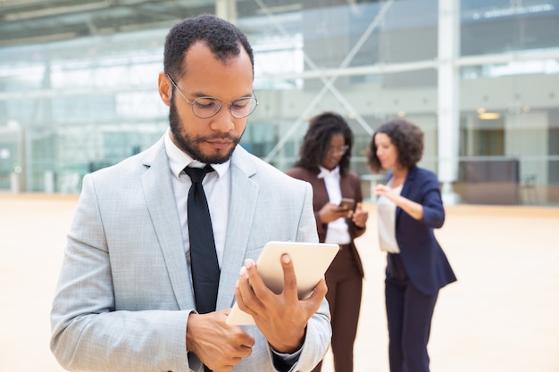 Homme d'affaires sérieux à l'aide d'une tablette à l'extérieur