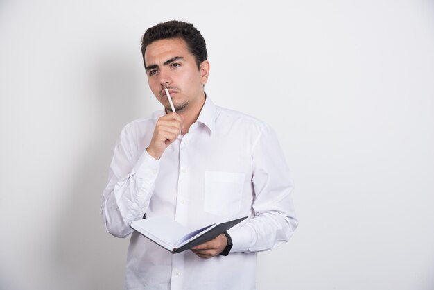 Homme d'affaires sérieux avec ordinateur portable réfléchissant dur sur fond blanc.