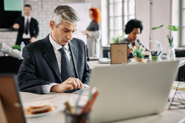 Homme d'affaires sérieux travaillant au bureau et analysant des plans d'affaires Il y a des gens en arrière-plan