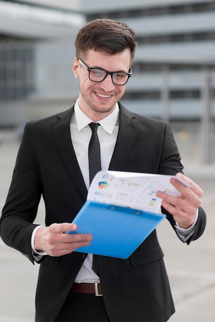 Photo gratuite homme d'affaires smiley vérifiant le presse-papiers