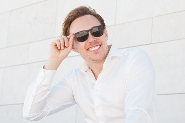 Homme d'affaires souriant, ajustant des lunettes de soleil à l'extérieur