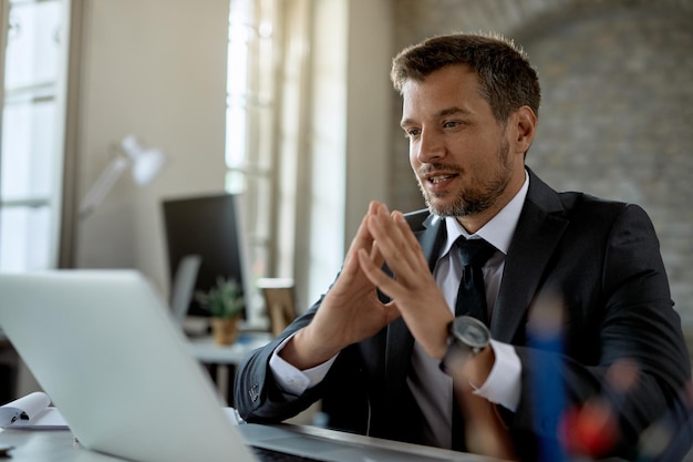 Homme d'affaires souriant lisant un e-mail sur un ordinateur portable tout en travaillant au bureau