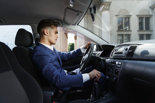 Homme d&#39;affaires souriant s&#39;assoit dans la voiture