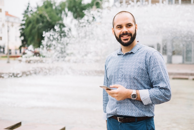 Photo gratuit homme d'affaires souriant avec téléphone au centre-ville