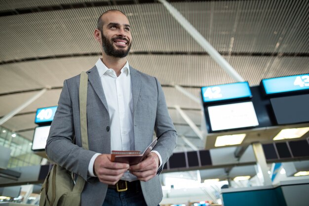 Homme d'affaires souriant tenant une carte d'embarquement et un passeport