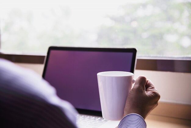 Homme d'affaires travaillant avec un ordinateur avec une tasse de café dans la chambre d'hôtel