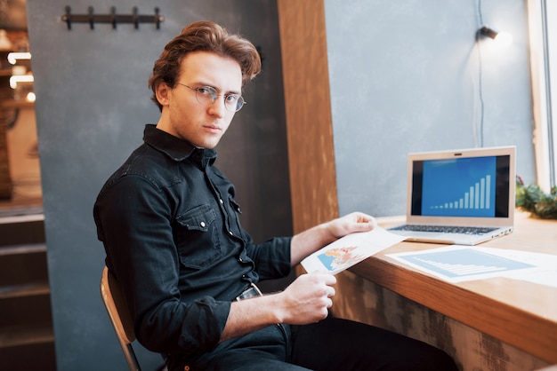 Homme d'affaires utilisant un ordinateur portable avec tablette et stylo sur une table en bois dans un café avec une tasse de café. Un entrepreneur qui gère son entreprise à distance en tant que pigiste.