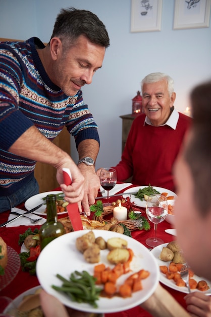 Homme affectueux coupant la viande de dinde