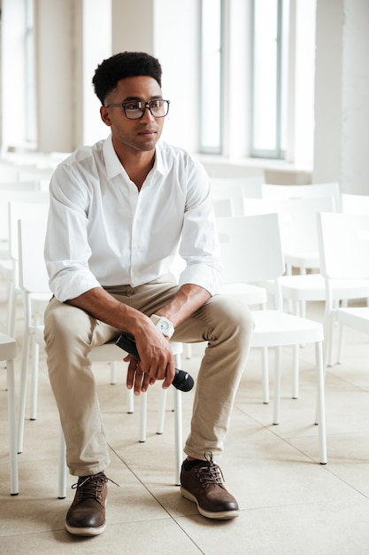 Photo gratuite homme africain concentré assis dans le bureau à l'intérieur