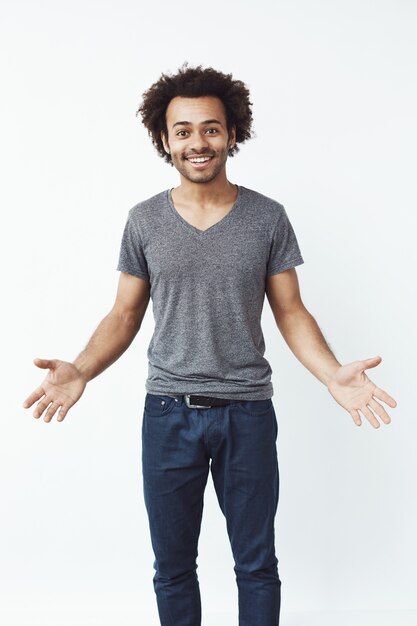 Homme africain élégant et beau avec les bras grands ouverts contre le mur blanc invitant à un concert.