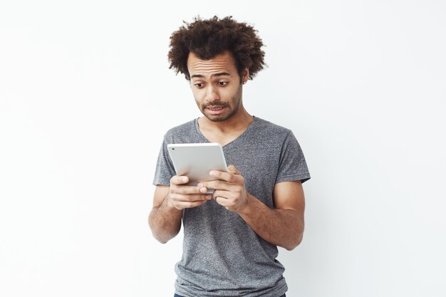 Homme africain mécontent en regardant tablette.