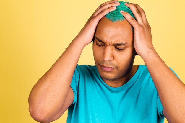 Homme africain noir en casual sur mur jaune fatigué stressant, tenant les mains sur la tête, ayant mal à la tête, douleur