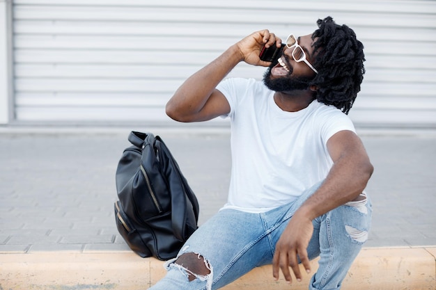 Photo gratuite homme africain noir souriant parlant au téléphone en plein air