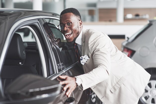 Homme africain à la recherche d'une nouvelle voiture chez le concessionnaire automobile.