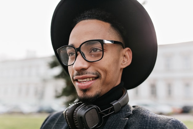 Homme africain rêveur avec de grands yeux bruns à la recherche de suite. Photo extérieure du beau modèle masculin noir posant