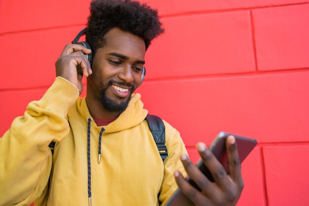 Homme afro à l'aide de sa tablette numérique avec des écouteurs.